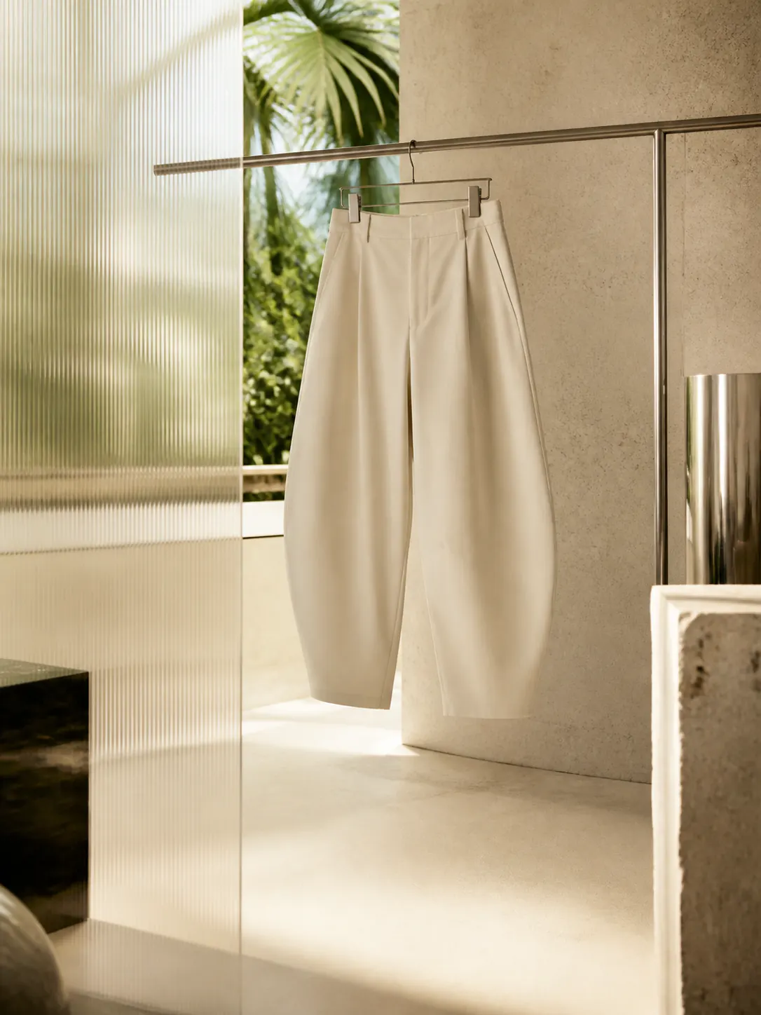 Editorial study of sculptural balloon-leg trousers in a sunlit studio
